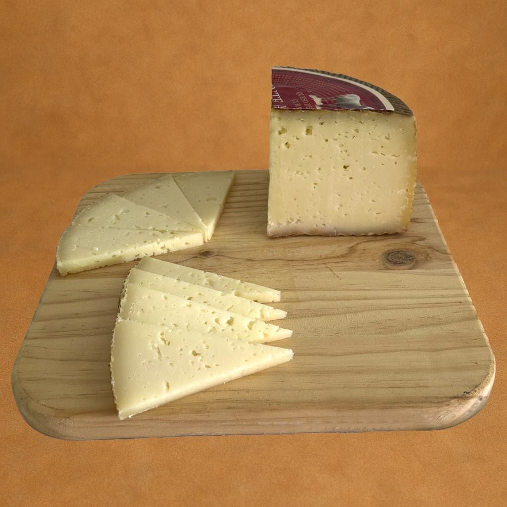 QUESO CURADO 1-4 FRONTAL Queso de oveja curado Fuente Albeitar, tabla de madera, pieza entera con etiqueta roja y fondo rústico.